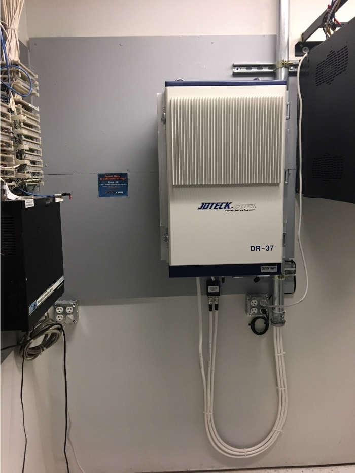 Illustrated here is JDTECK's new 37dBm Digital Repeater installed in a communications closet at a government facility. One box neatly installed in a corner of the room supports the services of all WSP's. 